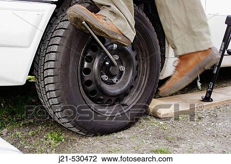 Man loosening the screws of a tire. View Large Photo Image Stock Image - Man loosening the screws of a tire.. Fotosearch