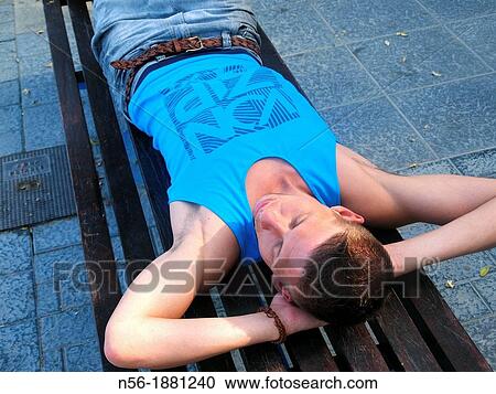 Man lying on a bench View Large Photo Image Stock Image - Man lying on a bench. Fotosearch