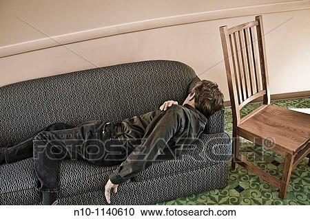 Man lying on a sofa in a college lounge View Large Photo Image Stock Image - Man lying on a sofa in a college lounge. Fotosearch
