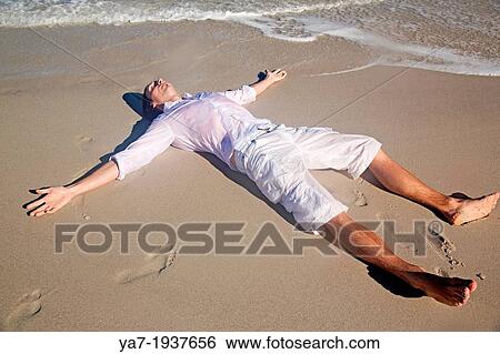 Stock Photograph - Man Lying on Beach. Fotosearch