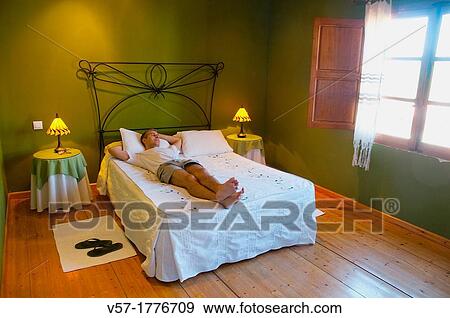 Man lying on bed in a rural hotel View Large Photo Image Stock Photo - Man lying on bed in a rural hotel. Fotosearch