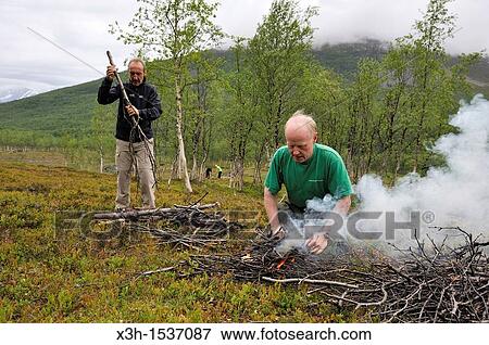 Stock Photo - man making a campfire, Nordmannvikdalen valley, region of Lyngen, County of Troms, Norway, Northern Europe. Fotosearch