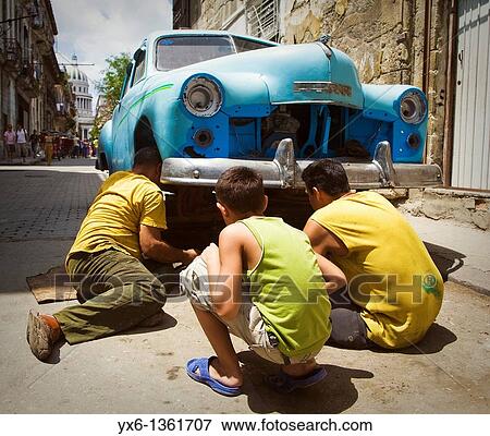Man man repairs a broken down car in the street while another man and a boy look on in Havana, Cuba View Large Photo Image Stock Photo - Man man repairs a broken down car in the street while another man and a boy look on in Havana, Cuba. Fotosearch