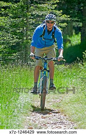 Stock Photo - Man mountain biking from Tonde De Faloria to Rio Gere high above the city of Cortina in northern Italy. Fotosearch