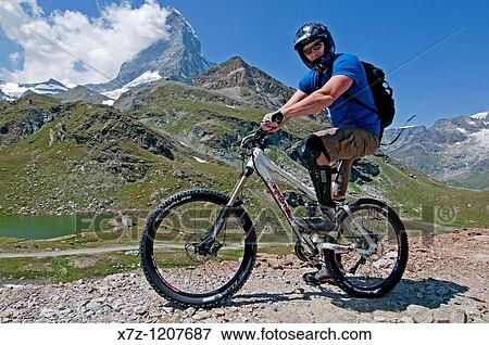 Man mountain biking in the shadow of The Matterhorn at Schwarzsee Paradise high in the Swiss Alps above the city of Zermatt in Switzerland View Large Photo Image Stock Photo - Man mountain biking in the shadow of The Matterhorn at Schwarzsee Paradise high in the Swiss Alps above the city of Zermatt in Switzerland. Fotosearch