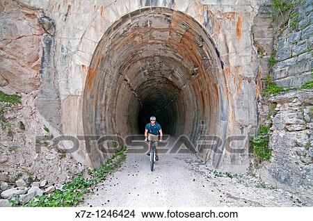 Man mountain biking through tunnels at Val Felizon above the city of Cortina in northern Italy View Large Photo Image Picture - Man mountain biking through tunnels at Val Felizon above the city of Cortina in northern Italy. Fotosearch