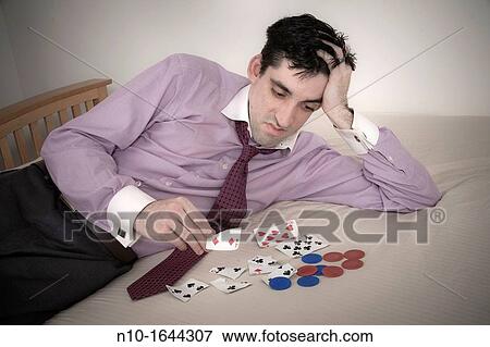Man on a bed with ripped playing cards and poker chips View Large Photo Image Stock Photo - Man on a bed with ripped playing cards and poker chips. Fotosearch