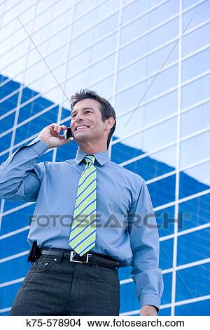 Man on cell phone outside modern building View Large Photo Image Picture - Man on cell phone outside modern building. Fotosearch