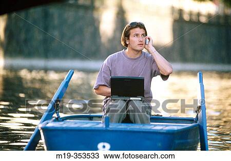 Man on rowboat using cellular phone and laptop View Large Photo Image Stock Image - Man on rowboat using cellular phone and laptop. Fotosearch