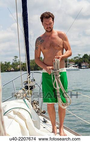 Picture - Man on sailboat.. Fotosearch