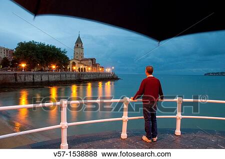 Stock Photo - Man on the promenade, night view. Gij? n, Asturias province, Spain.. Fotosearch
