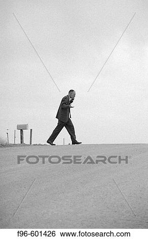 Man pacing on deserted road, talking on cell phone View Large Photo Image Stock Photograph - Man pacing on deserted road, talking on cell phone. Fotosearch