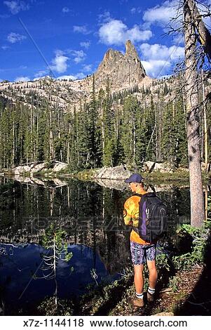 Man, pauses at a small lake while hiking to The Finger Of Fate for a rock climb of The Open Book route in the Sawtooth Mountains, Idaho View Large Photo Image Stock Photo - Man, pauses at a small lake while hiking to The Finger Of Fate for a rock climb of The Open Book route in the Sawtooth Mountains, Idaho. Fotosearch