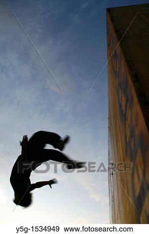 man performing parkour on roof top in city town at night View Large Photo Image Stock Photo - man performing parkour on roof top in city town at night. Fotosearch