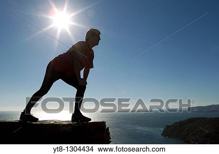 Man performing stretching exercise by the sea View Large Photo Image Picture - Man performing stretching exercise by the sea. Fotosearch