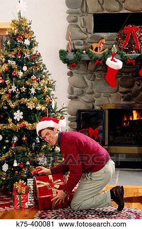 Man placing presents under Christmas tree View Large Photo Image Stock Image - Man placing presents under Christmas tree. Fotosearch