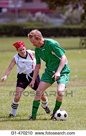 Man playing soccer against a woman on field during a game View Large Photo Image Stock Image - Man playing soccer against a woman on field during a game. Fotosearch