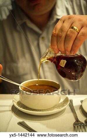 Picture - Man pouring rum in a dish of Bermudian fish chowder. Fotosearch