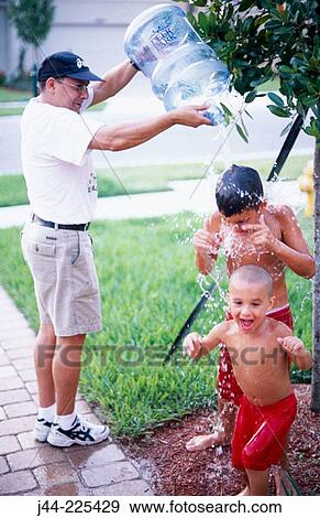 Man pouring water to kids from bottle in the garden View Large Photo Image Stock Photo - Man pouring water to kids from bottle in the garden. Fotosearch