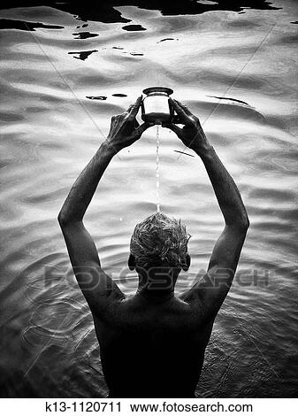 Stock Image - Man praying in a Ganges river Varanasi Uttar Pradesh India. Fotosearch