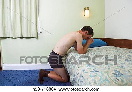 Man praying in sparse hotel room View Large Photo Image Picture - Man praying in sparse hotel room. Fotosearch