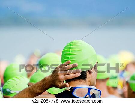 Man preparing for the triathlon start with green bathing cap and swimming goggles in switzerland. View Large Photo Image Stock Photo - Man preparing for the triathlon start with green bathing cap and swimming goggles in switzerland.. Fotosearch