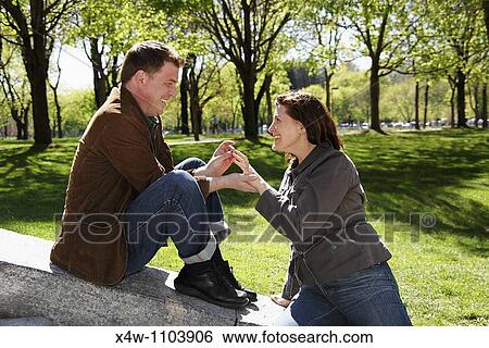Man proposing to woman on a beautiful sunny day in a park View Large Photo Image Stock Photograph - Man proposing to woman on a beautiful sunny day in a park. Fotosearch