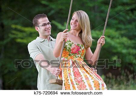 Man pushing girlfriend on swing View Large Photo Image Picture - Man pushing girlfriend on swing. Fotosearch