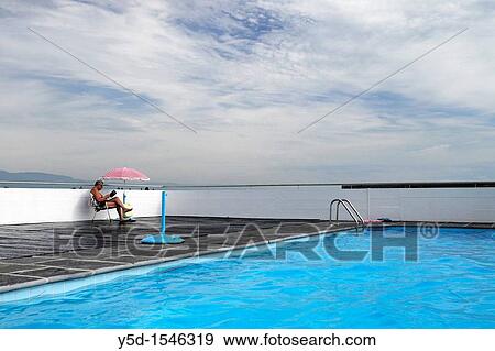 man reading a book and resting at swimming pool View Large Photo Image Stock Photo - man reading a book and resting at swimming pool. Fotosearch