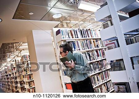 Man reading a book in the library View Large Photo Image Stock Photograph - Man reading a book in the library. Fotosearch