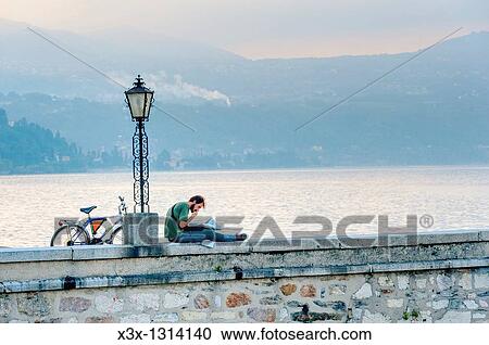 Man reading a newspaper in the town of Arona Lago Maggiore Italy View Large Photo Image Stock Image - Man reading a newspaper in the town of Arona Lago Maggiore Italy. Fotosearch