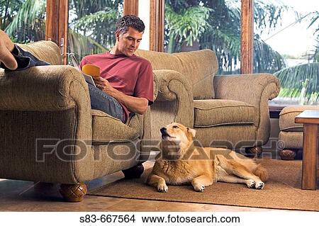 Man reading on chair with dog on floor next to him View Large Photo Image Picture - Man reading on chair with dog on floor next to him. Fotosearch