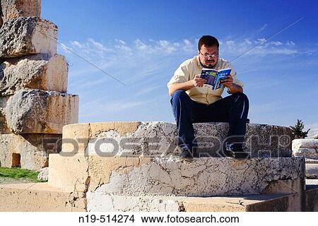 Man reading travel guide on steps of Roman temple, Baalbek, Lebanon View Large Photo Image Picture - Man reading travel guide on steps of Roman temple, Baalbek, Lebanon. Fotosearch