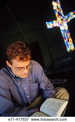 Man reads a Bible in church, stained glass window in background. View Large Photo Image Stock Photo - Man reads a Bible in church, stained glass window in background.. Fotosearch