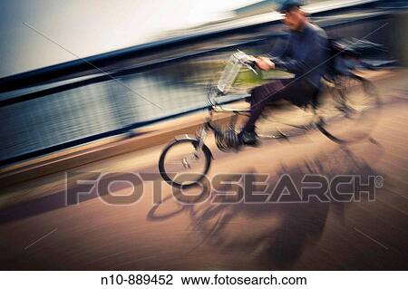 Stock Image - Man riding a recumbent bicycle on a footbridge.. Fotosearch