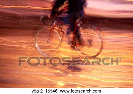 man riding bike at night in street road in city town View Large Photo Image Stock Photograph - man riding bike at night in street road in city town. Fotosearch