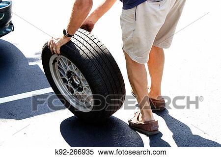 Man rolling a tire to be changed View Large Photo Image Stock Photography - Man rolling a tire to be changed. Fotosearch