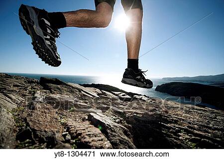 Man running along a rocky coastal path View Large Photo Image Stock Image - Man running along a rocky coastal path. Fotosearch