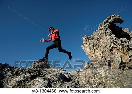 Man running and jumping over rocky terrain View Large Photo Image Stock Photo - Man running and jumping over rocky terrain. Fotosearch