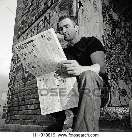 Man seated in doorway, reading a newspaper View Large Photo Image Stock Photo - Man seated in doorway, reading a newspaper. Fotosearch