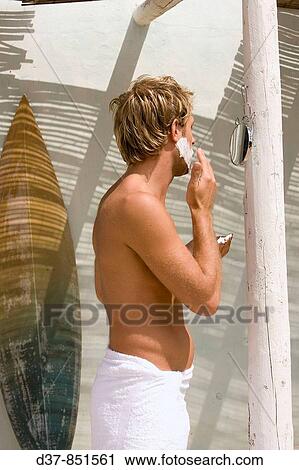 Stock Image - Man shaving in the morning in a beach hut. Fotosearch