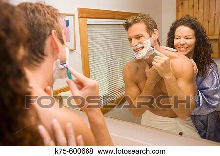 Stock Photo - Man shaving while wife watches. Fotosearch
