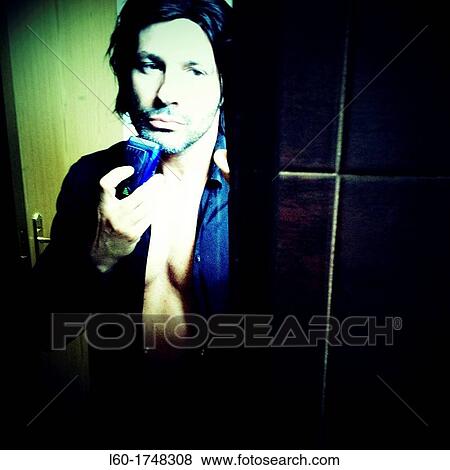 Stock Photo - Man shaving with electric razor, Portrait. Fotosearch