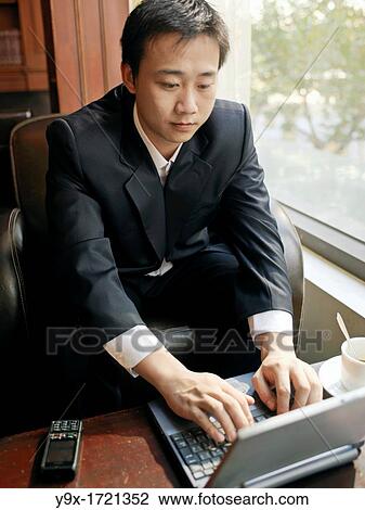 Man sits by a window utilizing his laptop for communication View Large Photo Image Stock Image - Man sits by a window utilizing his laptop for communication. Fotosearch