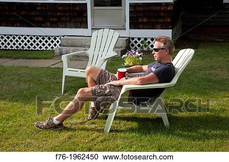 Man sitting and relaxing in adirondack lawn chair on lawn with red plastic cup View Large Photo Image Stock Image - Man sitting and relaxing in adirondack lawn chair on lawn with red plastic cup. Fotosearch