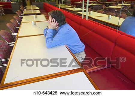 Man sitting at a table in an empty employees? cafeteria. View Large Photo Image Stock Photo - Man sitting at a table in an empty employees? cafeteria.. Fotosearch