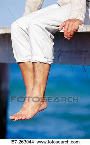 Man sitting down in a wooden footbridge over the sea View Large Photo Image Picture - Man sitting down in a wooden footbridge over the sea. Fotosearch