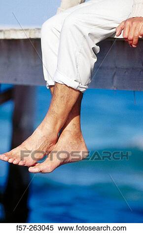 Man sitting down in a wooden footbridge over the sea View Large Photo Image Stock Photography - Man sitting down in a wooden footbridge over the sea. Fotosearch