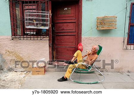 Man sitting in chair smoking cigar in Cienfuegos, Cuba View Large Photo Image Stock Image - Man sitting in chair smoking cigar in Cienfuegos, Cuba. Fotosearch