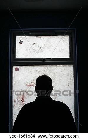 Picture - man sitting in dark room. Fotosearch